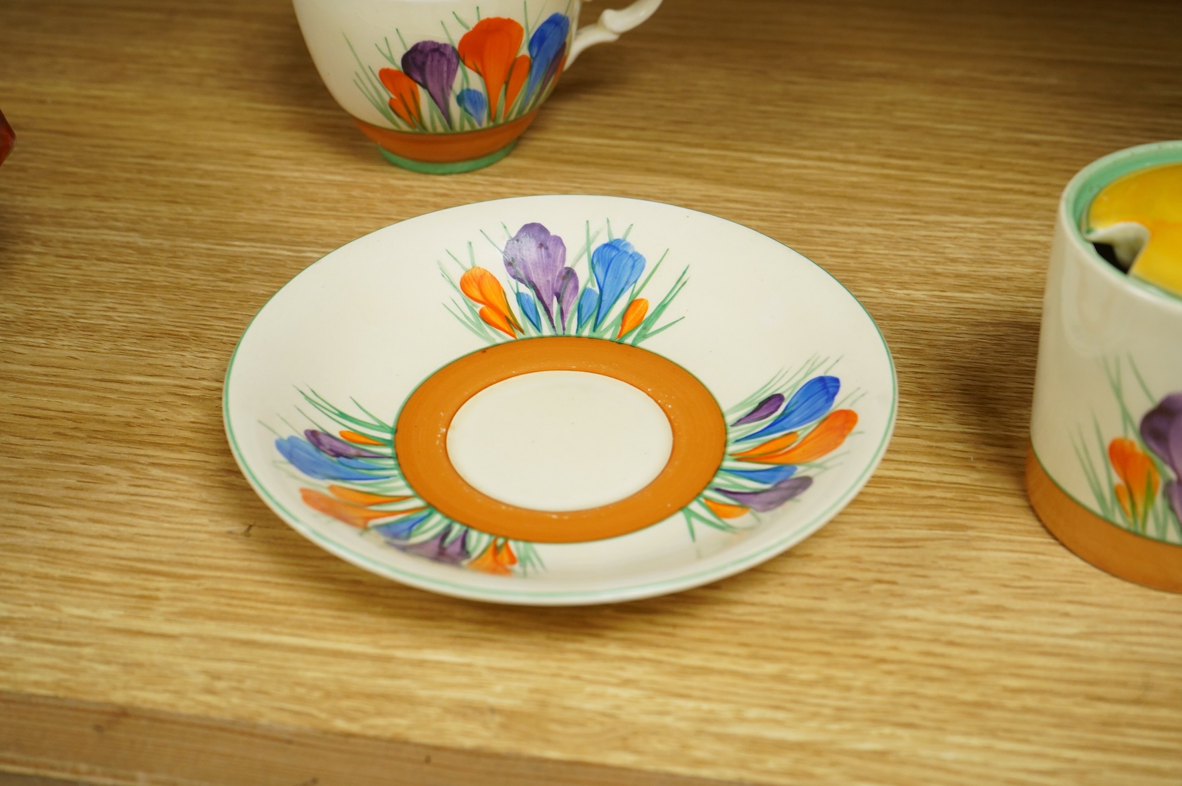A Clarice Cliff ‘crocus’ pattern preserve jar and cover, 10cm high and a similar cup and saucer